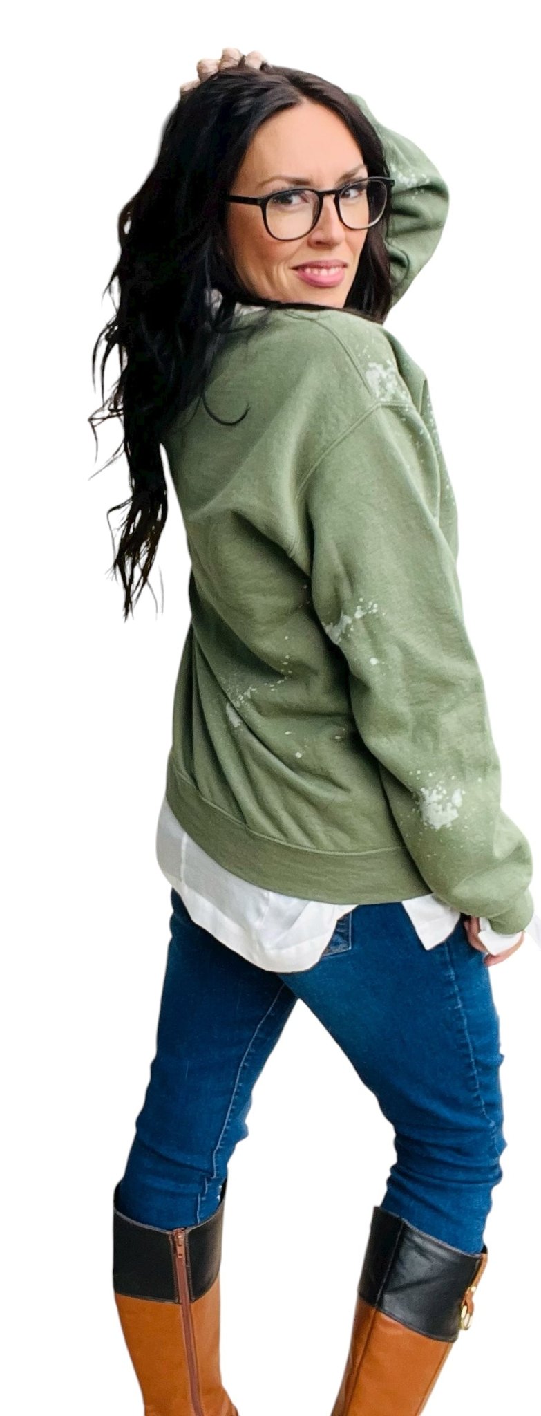 Person wearing a green sweater with white paint splashes, blue jeans, and brown boots on a white background