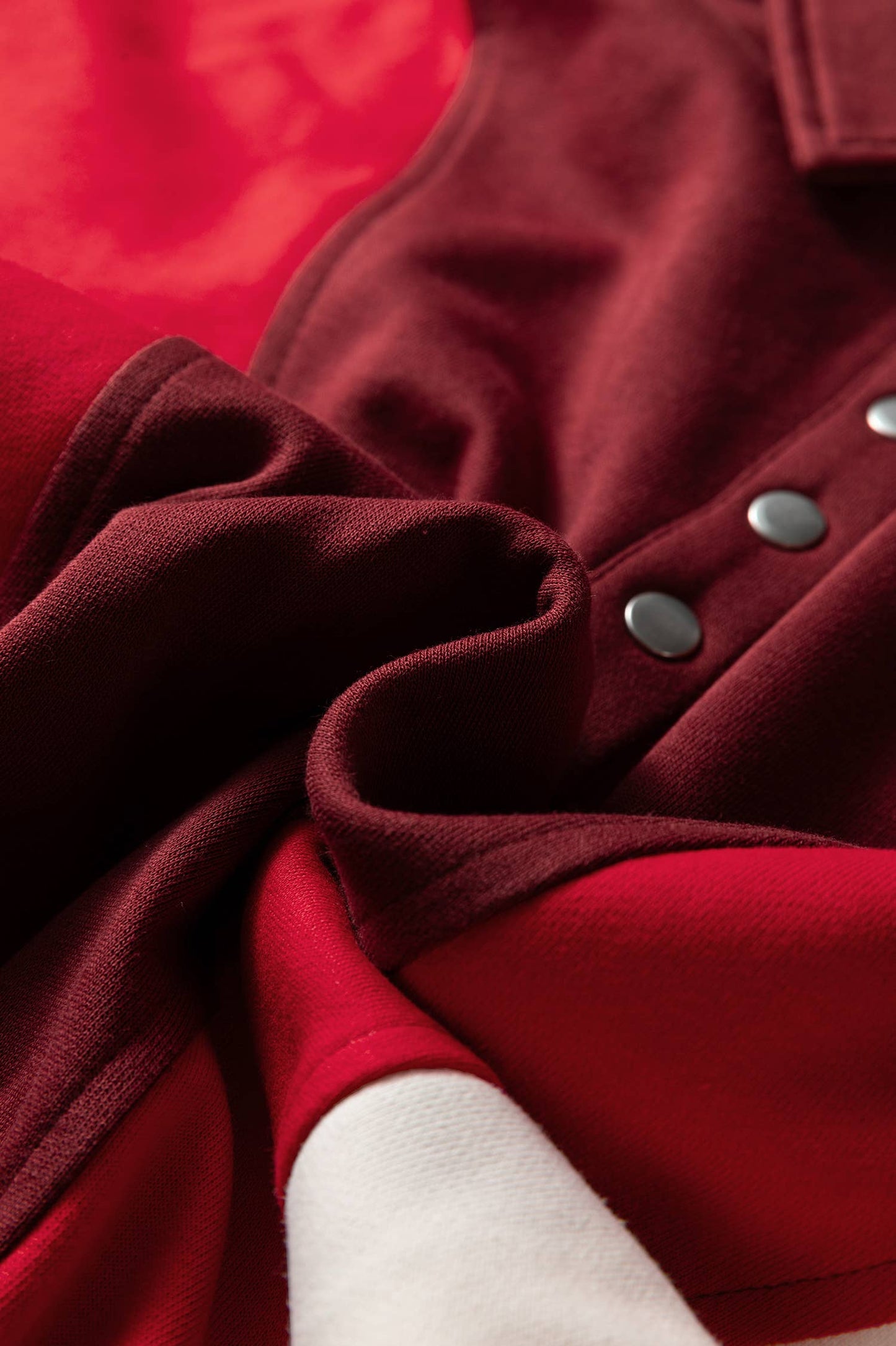 Close-up of a red coat with buttons and a white sleeve.