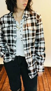 Person wearing a black and white checkered shirt over a plain shirt.