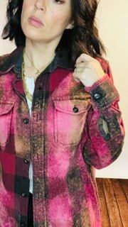 Person wearing a plaid jacket with a pink and brown pattern.