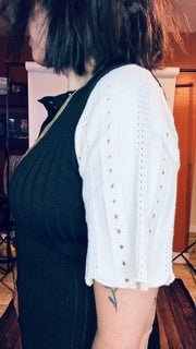 Person wearing a black dress with a white lace top in an indoor setting