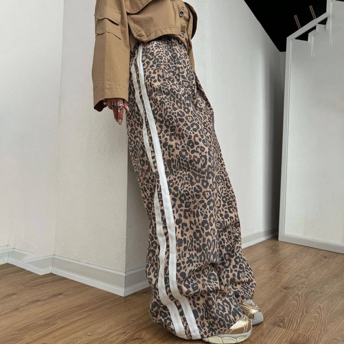 Person wearing leopard print pants with white stripes indoors.
