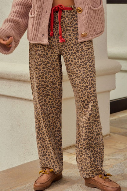 Person wearing leopard print pants with a pink knitted cardigan.