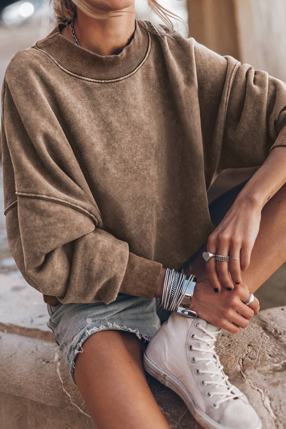 Women's brown oversized sweatshirt styled with denim shorts