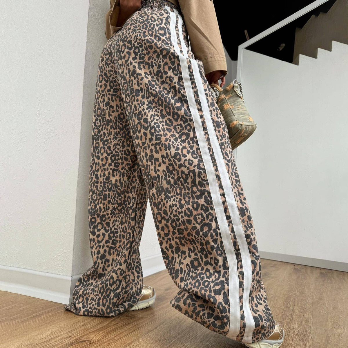 Person wearing leopard print pants with white stripes indoors.