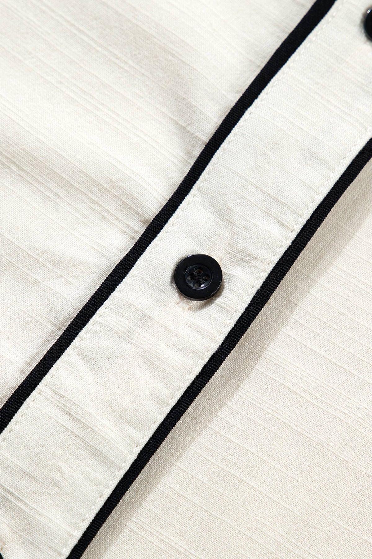Close-up of a button on a white shirt with black trim
