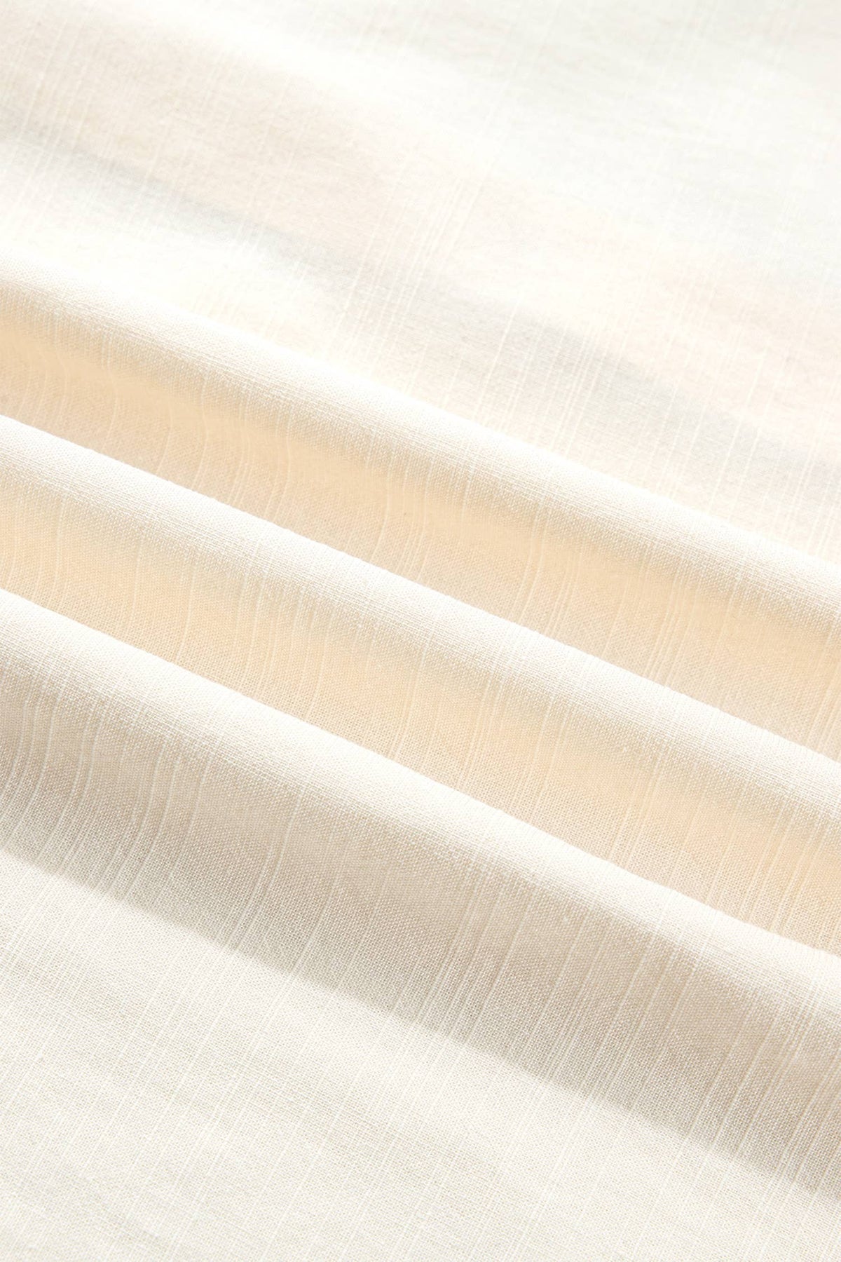 A close-up of draped off-white fabric with a subtle warm beige cast and fine textured folds.