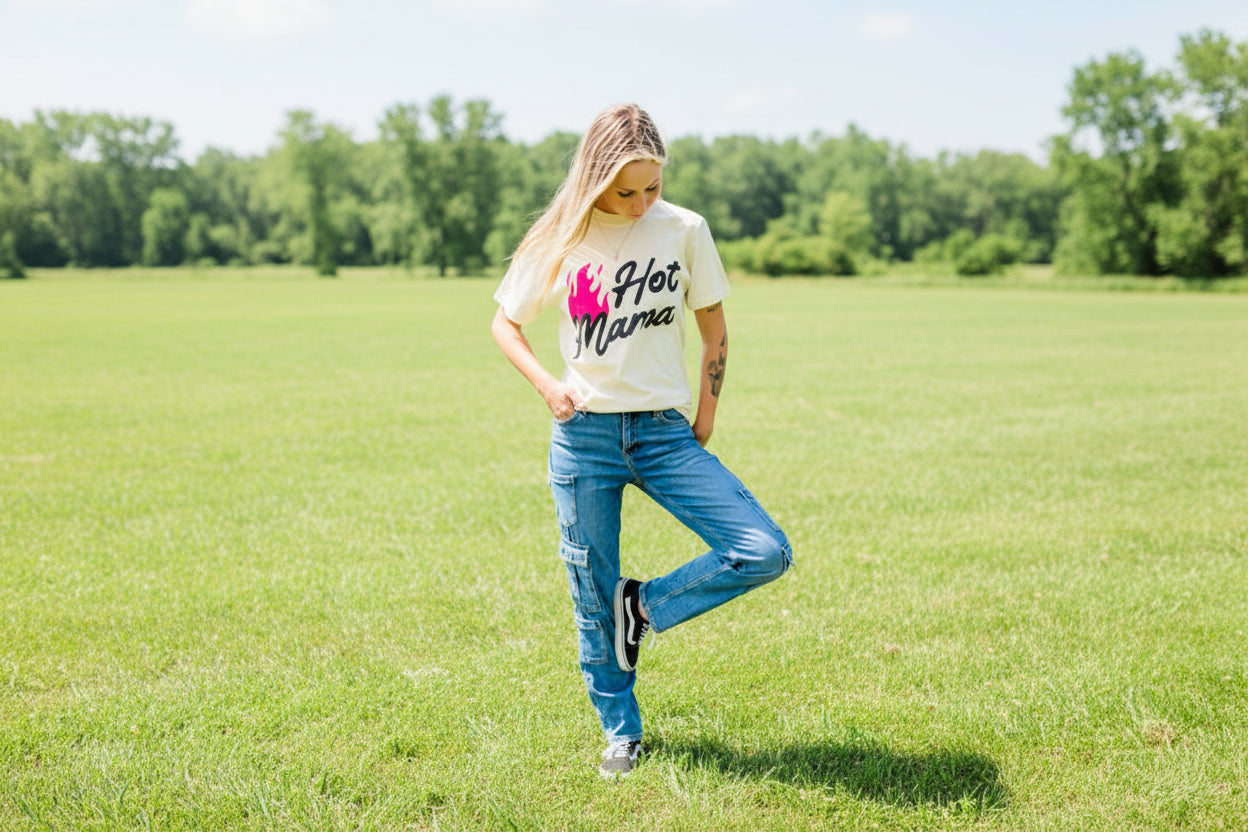 Person wearing a 'Hot Mama' t-shirt against a gray brick wall.