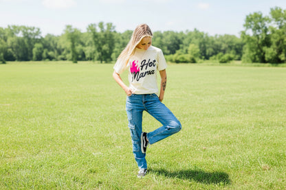 Person wearing a 'Hot Mama' t-shirt against a gray brick wall.