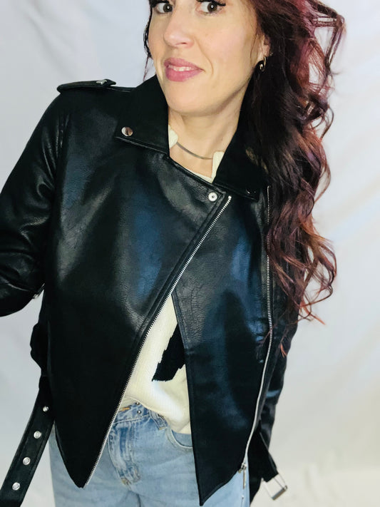 Woman wearing a black leather jacket against a plain background