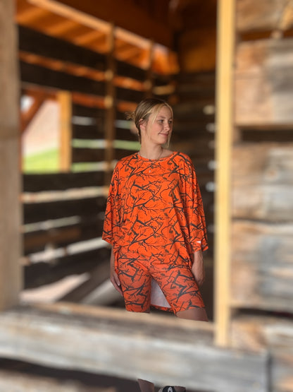 Person wearing an orange patterned dress standing inside a wooden structure.