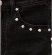 Close-up of black denim jeans showing the front pocket with silver stud embellishments.