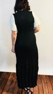 Person wearing a black dress with white sleeves and gold necklace.