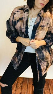 Person wearing a patterned jacket over a plain shirt with dark pants on a wooden floor.