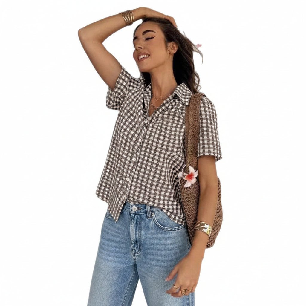 Woman wearing a checkered shirt and white shorts with a floral bag on a white background