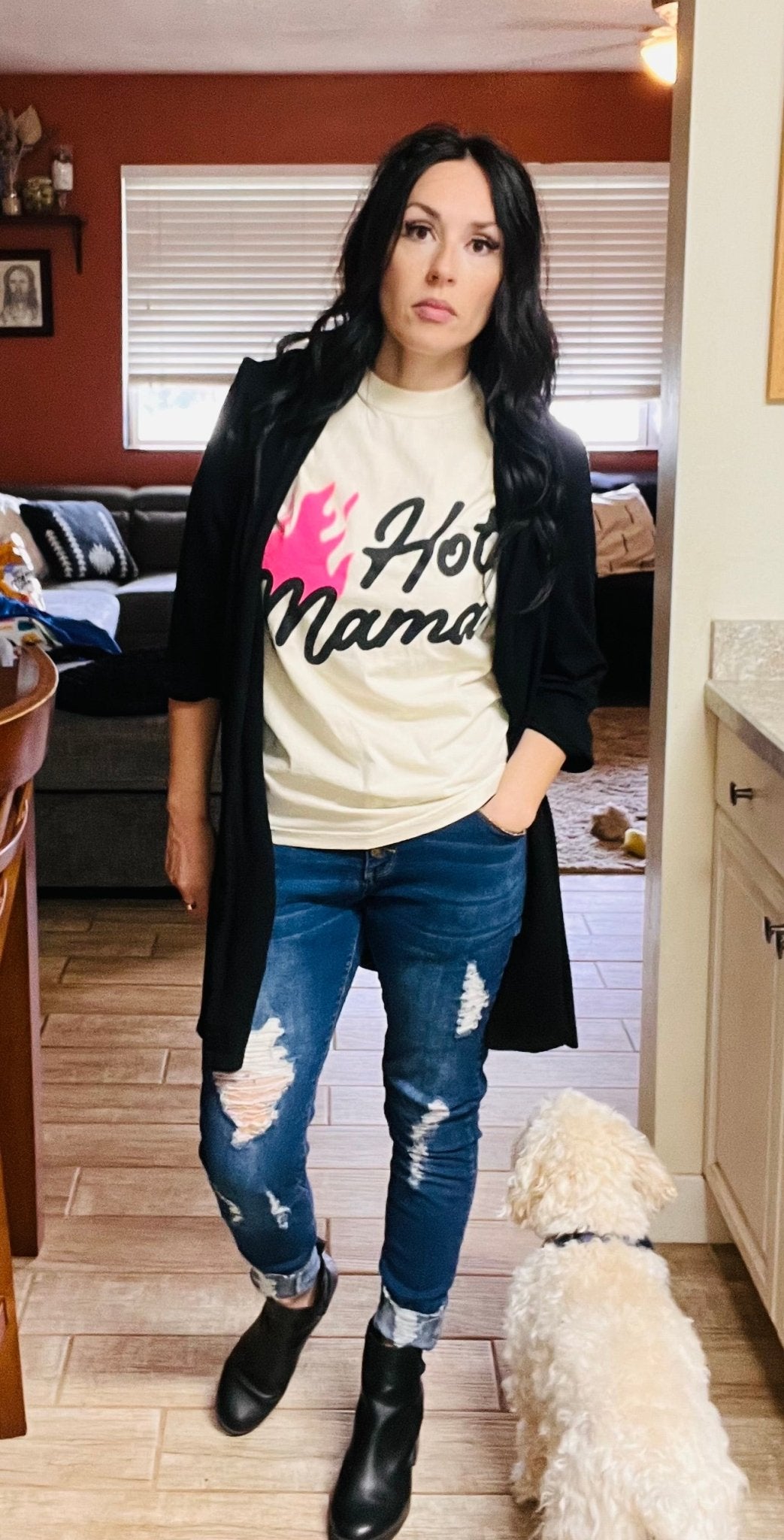 Woman wearing a 'Hot Mama' t-shirt with a dog in a living room.