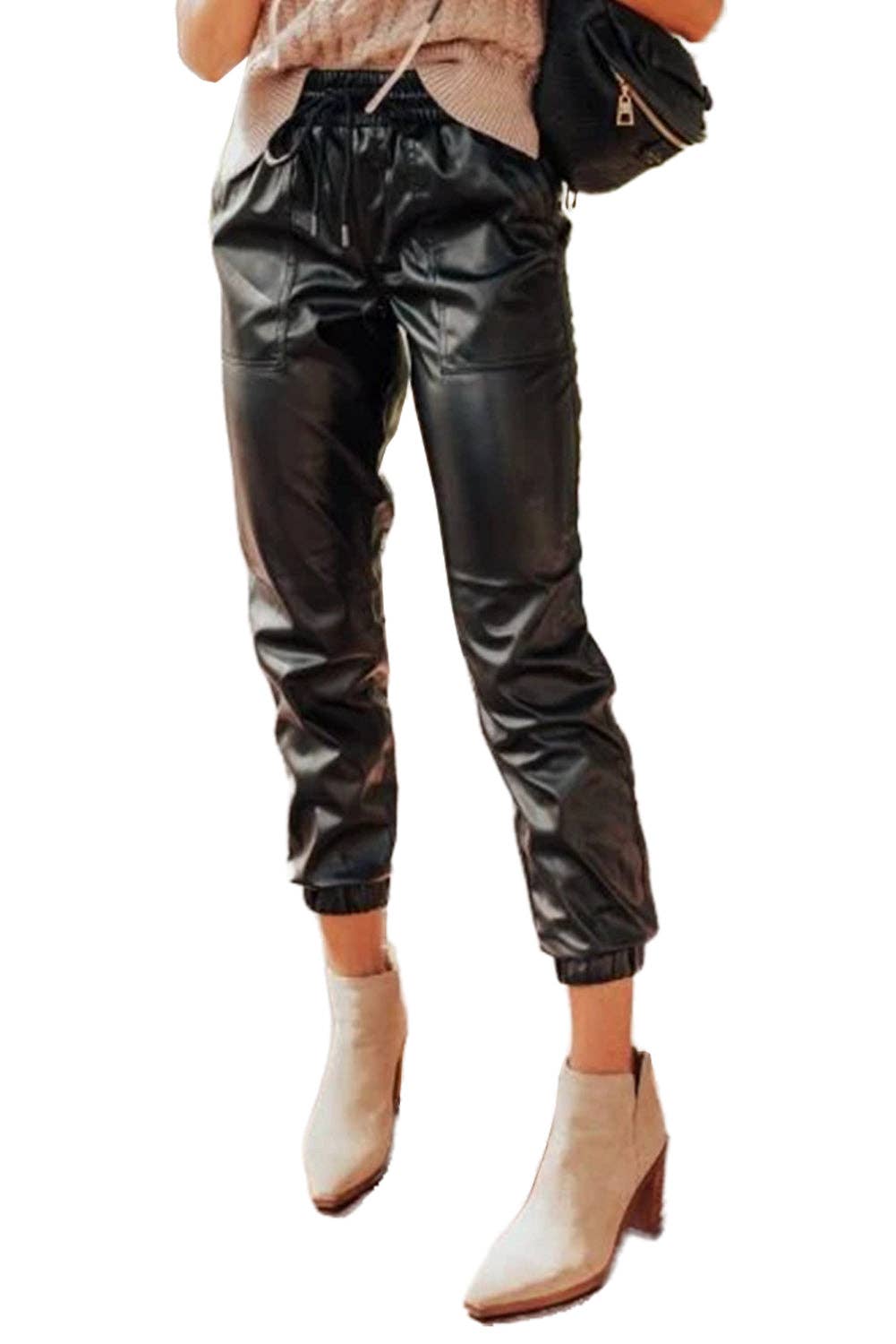 Person wearing black leather jogger pants and beige ankle boots on a white background