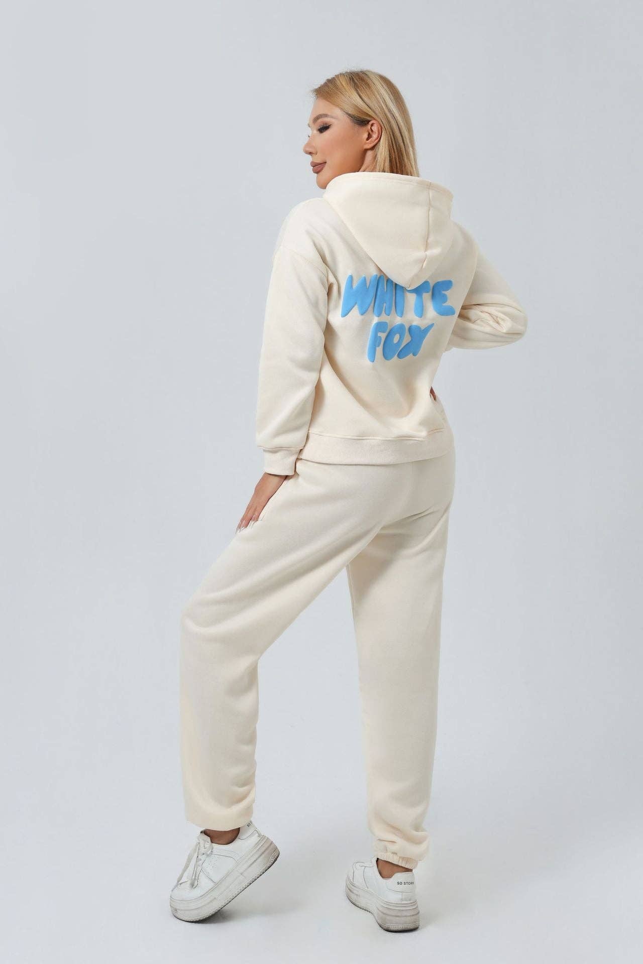 Person wearing a cream tracksuit with 'White Fox' branding on the back against a white background