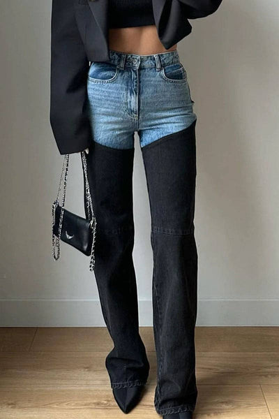 Person wearing a black blazer, blue denim shorts, and black flared jeans holding a black handbag.