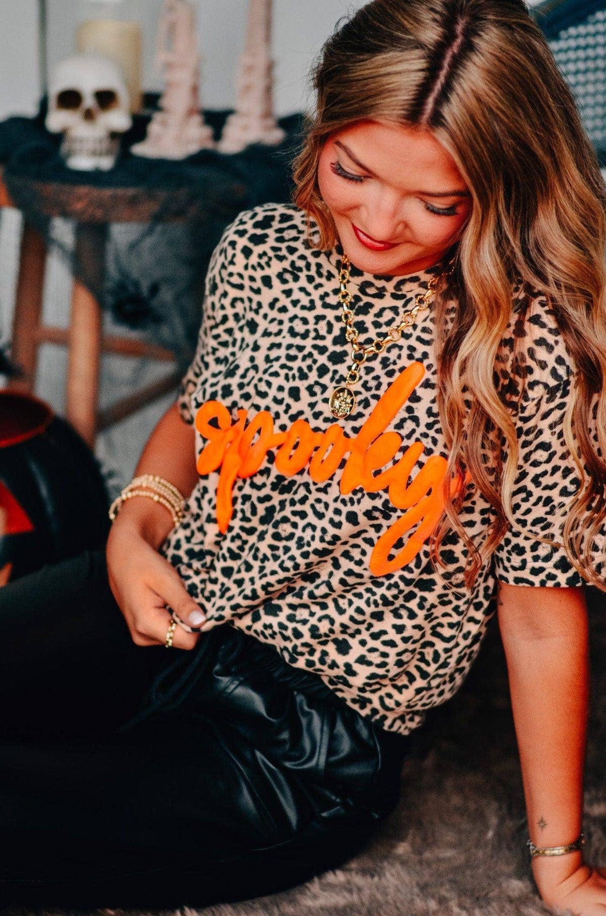 Person wearing a leopard print shirt with orange text, sitting on the floor.