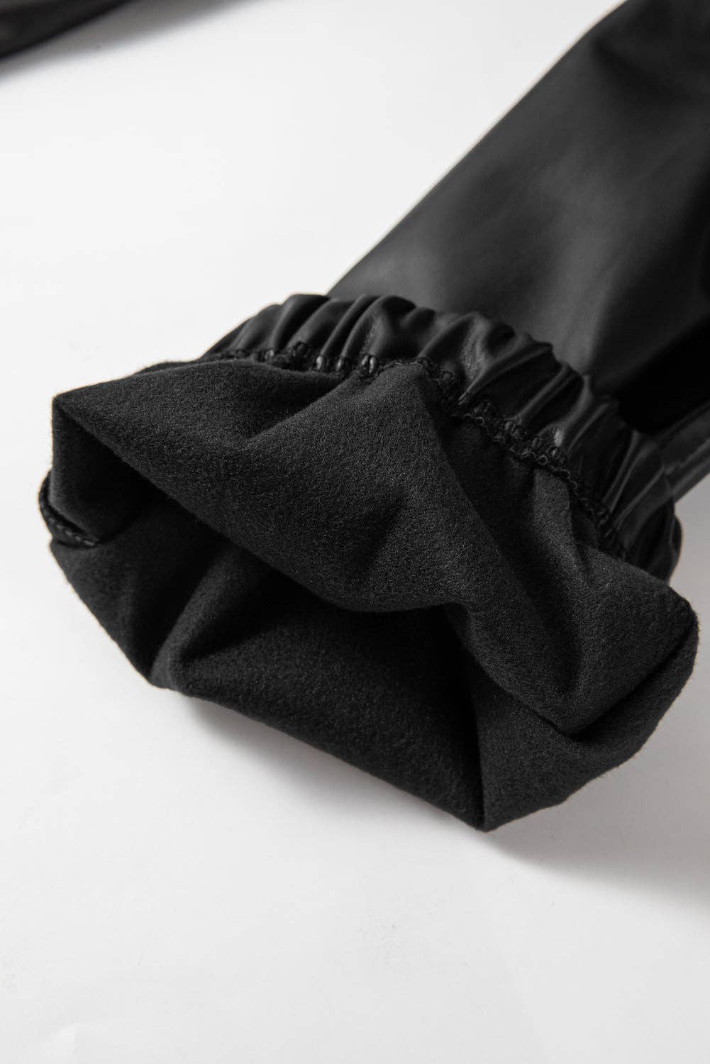 Close-up of a black sleeve with a ruffled cuff on a white background