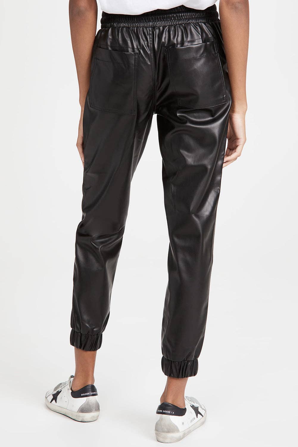 Black leather jogger pants worn by a person on a white background