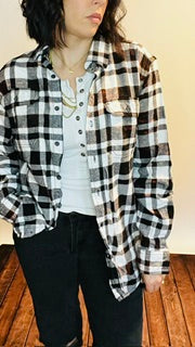 Person wearing a black and white checkered shirt over a plain shirt.