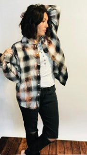 Person wearing a plaid shirt over a white shirt with black pants on a plain background