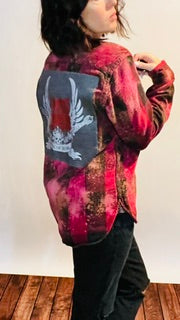 Person wearing a red and black patterned jacket with a graphic design on a wooden floor.