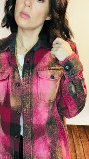 Person wearing a plaid jacket with a pink and brown pattern.