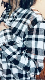 Close-up of a person wearing a plaid shirt with black, white, and gray patterns.
