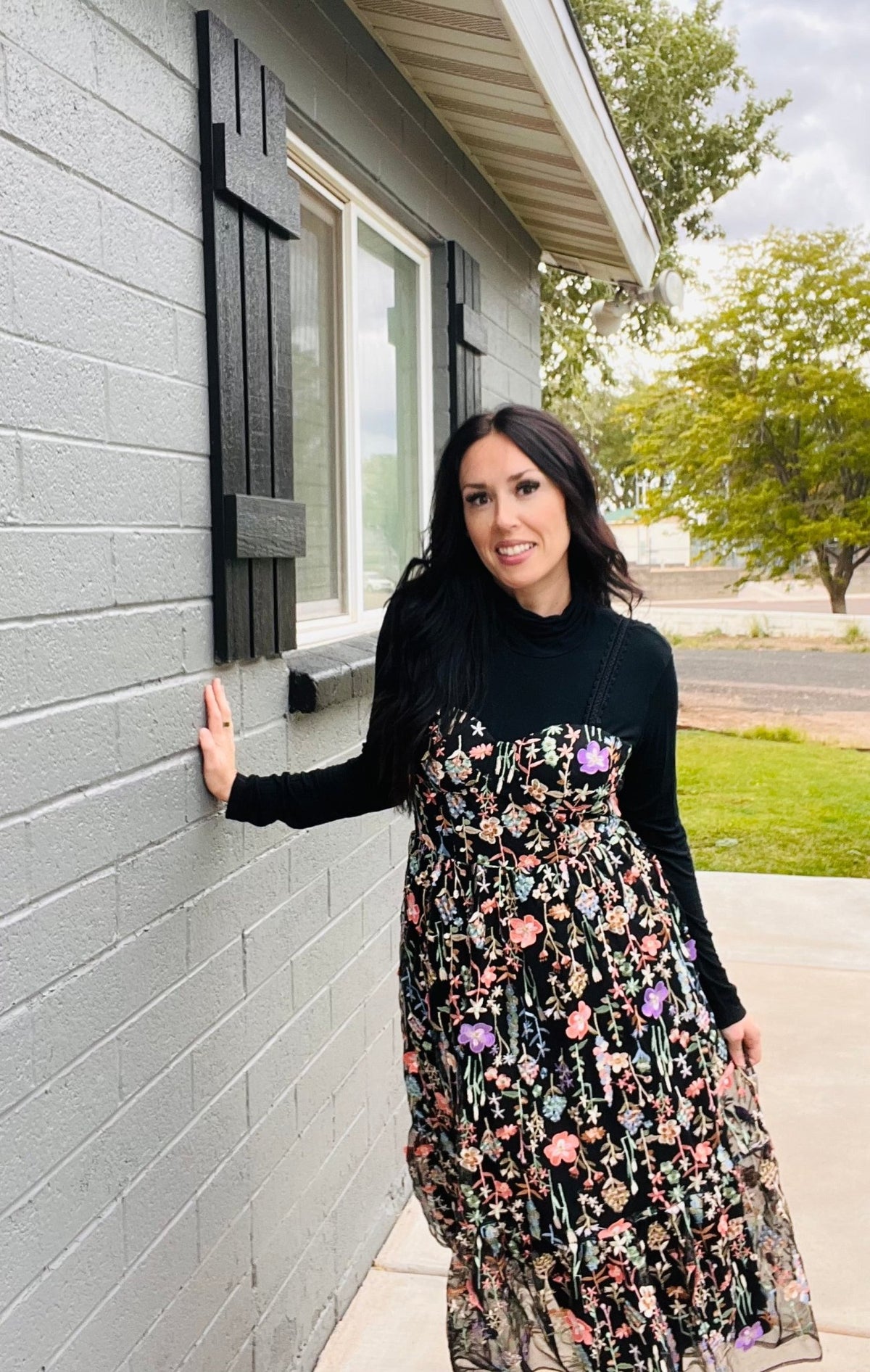 Woman in a floral dress standing next to a gray building