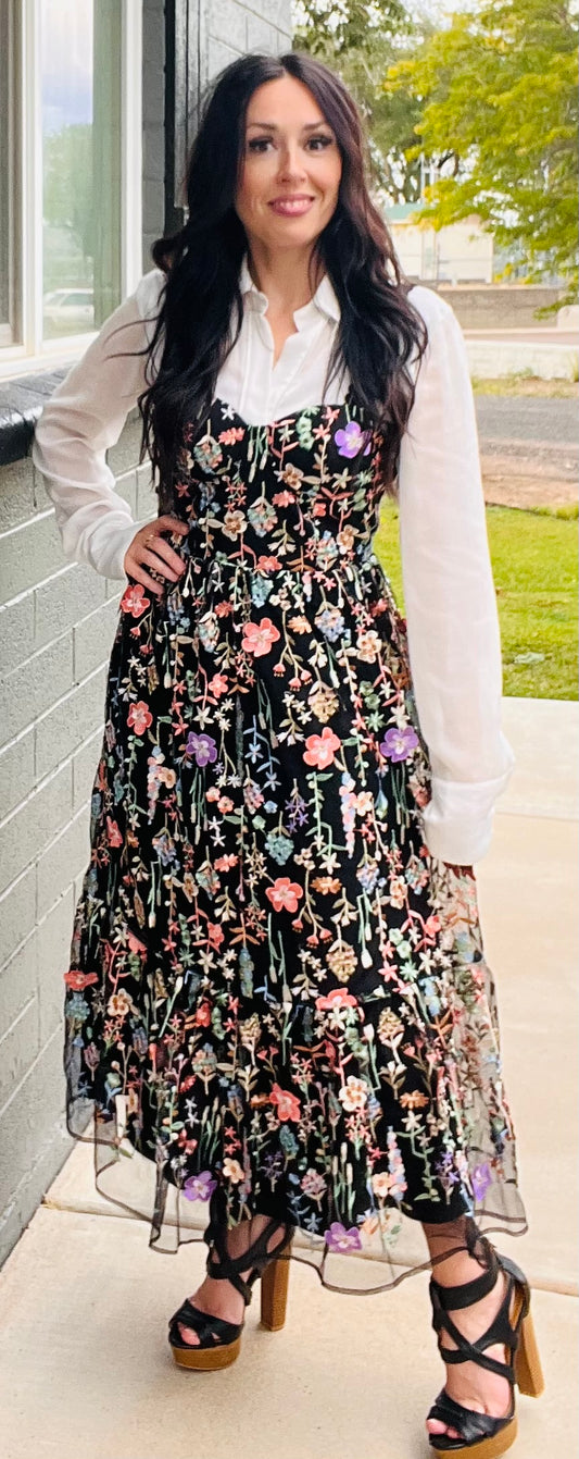 Woman wearing a floral dress with a white shirt, standing outdoors.