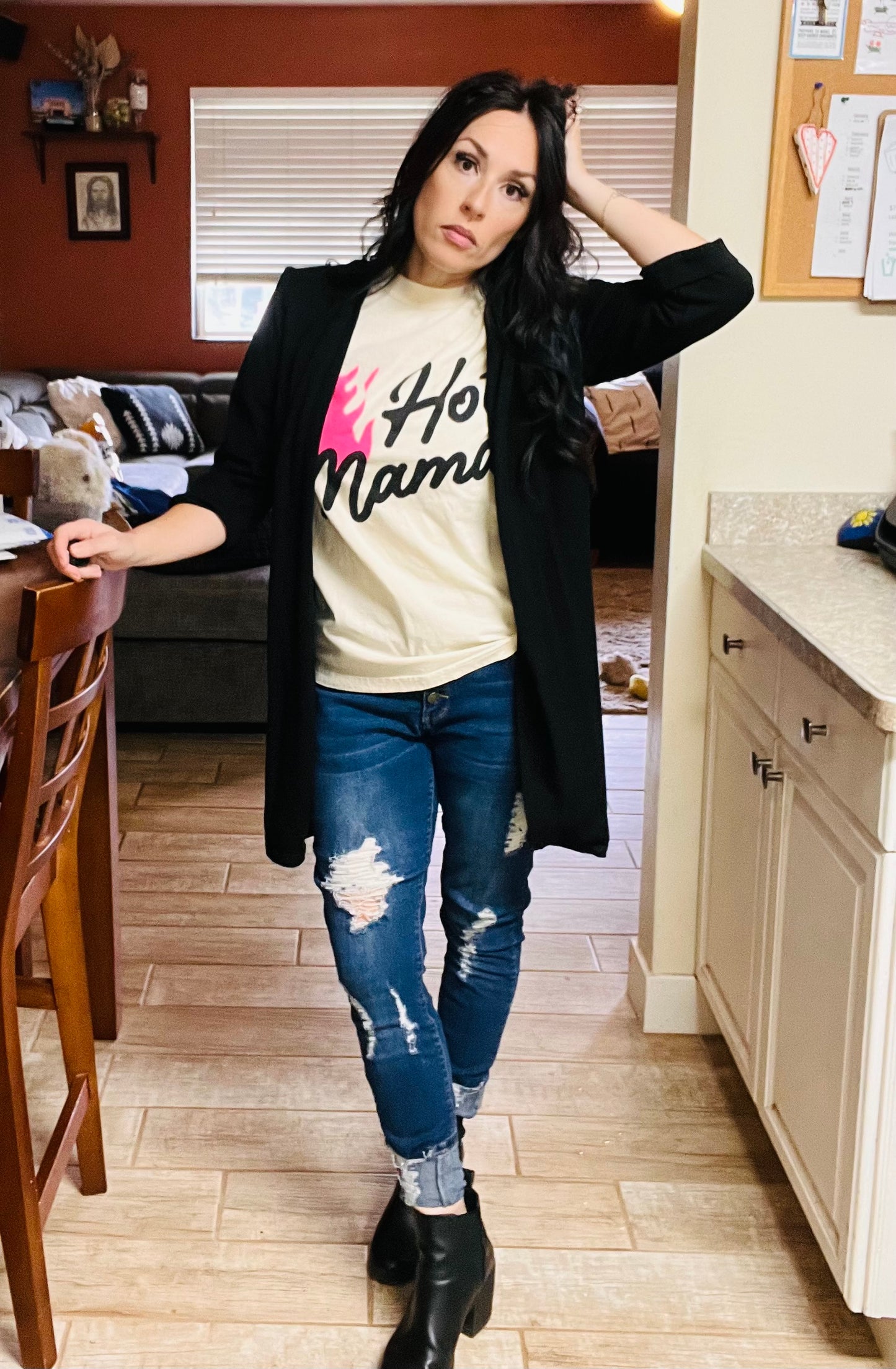 Woman in a kitchen wearing a 'Hot Mama' t-shirt and ripped jeans.