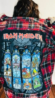 Person wearing a plaid shirt with Iron Maiden logo and stained glass design.
