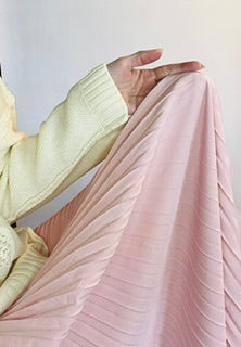 Person holding a pink pleated fabric against a light background