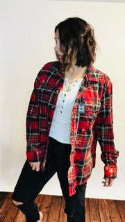 Person wearing a red and black plaid shirt with a white wall background