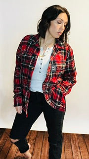 Person wearing a red and black plaid jacket indoors against a white wall.
