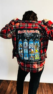 Person wearing a plaid shirt with Iron Maiden album cover designs on a white background