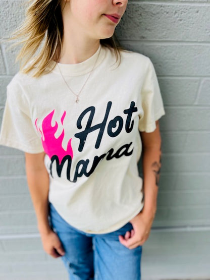 Person wearing a white t-shirt with 'Hot Mama' text and pink graphic against a gray wall.