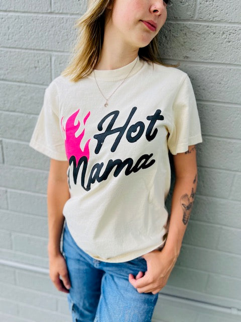 Person wearing a 'Hot Mama' t-shirt against a gray brick wall