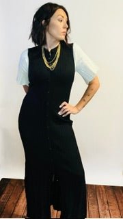Person wearing a black dress with white sleeves and gold necklace.