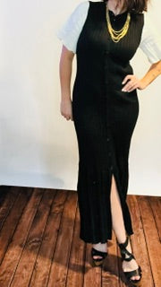 Person wearing a black dress with white sleeves and gold necklace.