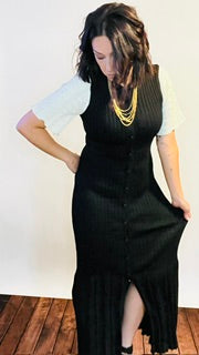 Person wearing a black dress with white sleeves and gold necklace.