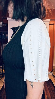Person wearing a black dress with a white lace top in an indoor setting